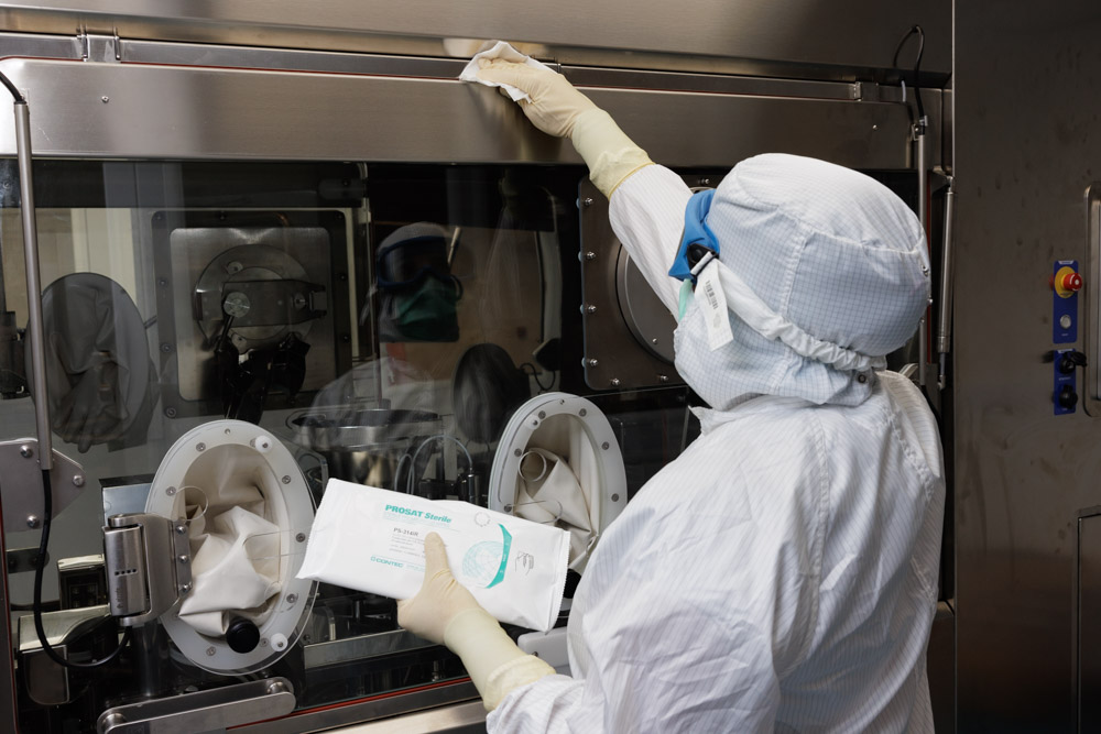 person in white hazmat suit cleaning a surface with wipes