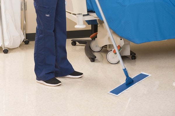 shot of nurses legs in scrubs wiping floor with blue swiffer mop