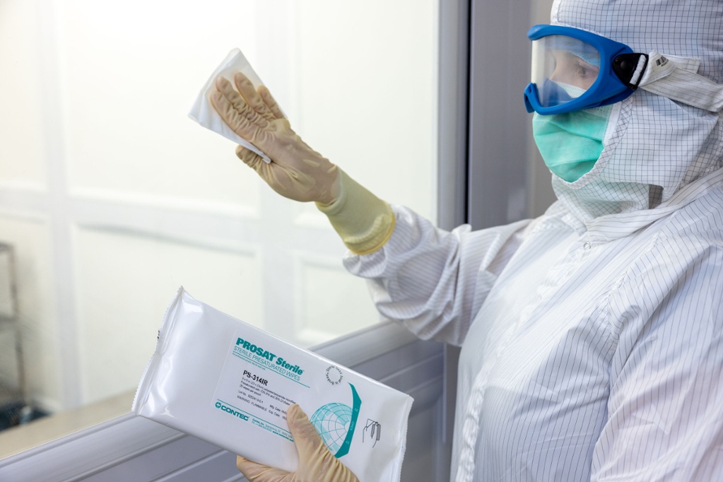 person in white hazmat suit cleaning window with wipes