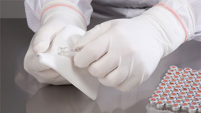gloved hand preparing injection vials